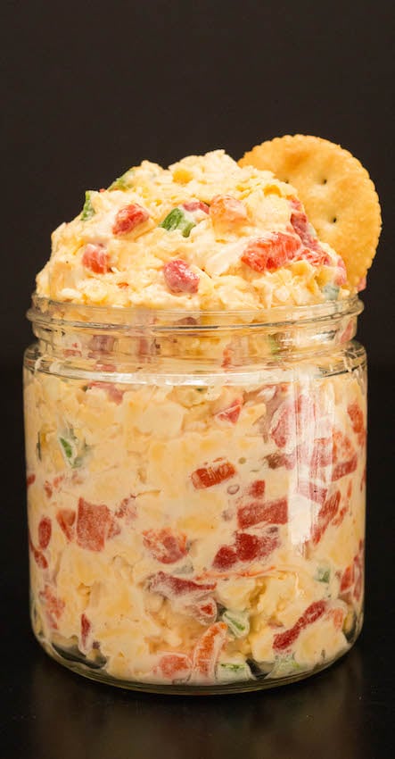 Homemade Pimento Cheese Recipe in a glass jar on a black background.
