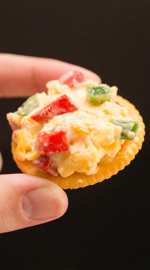 Fingers holding a Ritz cracker with Pimento Cheese.
