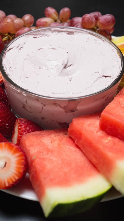 A bowl of Red Wine Fruit Dip surrounded by various fruits.