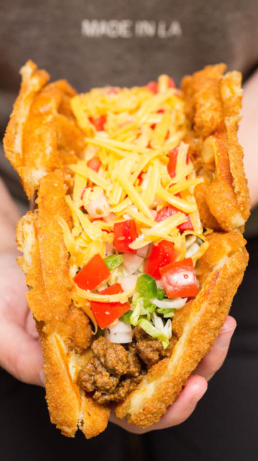 A hand holds up a Mozzarella Stick Taco.