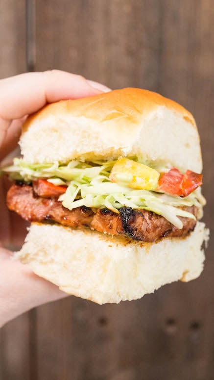 A hand holds up a Grilled Pork Loin Hawaiian Roll Slider.