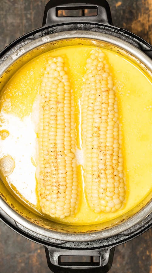 Two ears of corn floating in a milk & honey bath in the Instant Pot.