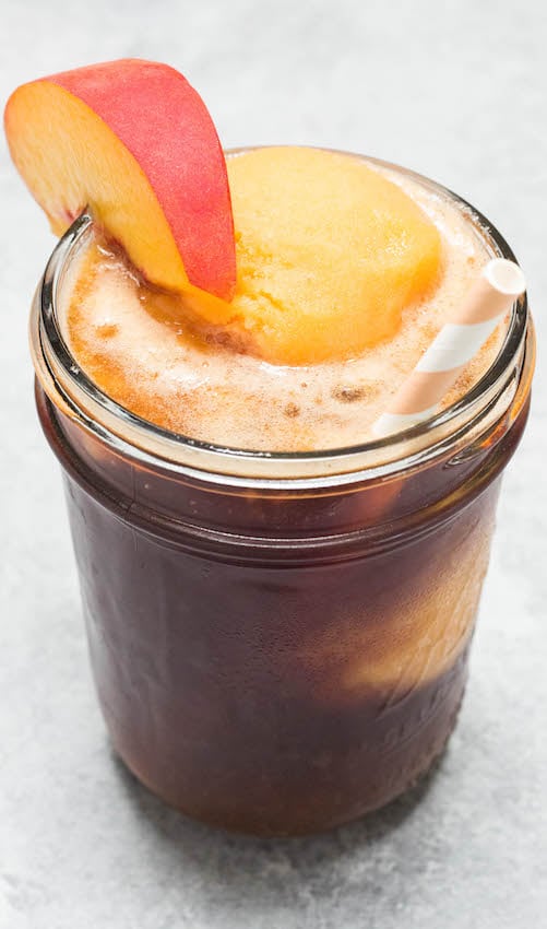 Sweet Tea Float with Peach Sorbet Ice Cream in a mason jar with a paper straw and fresh peach slice.