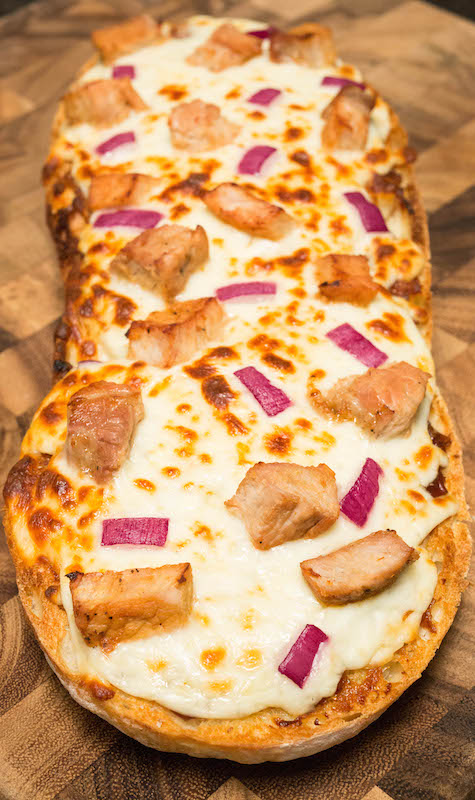 BBQ Pork French Bread pizza on a wood cutting board.