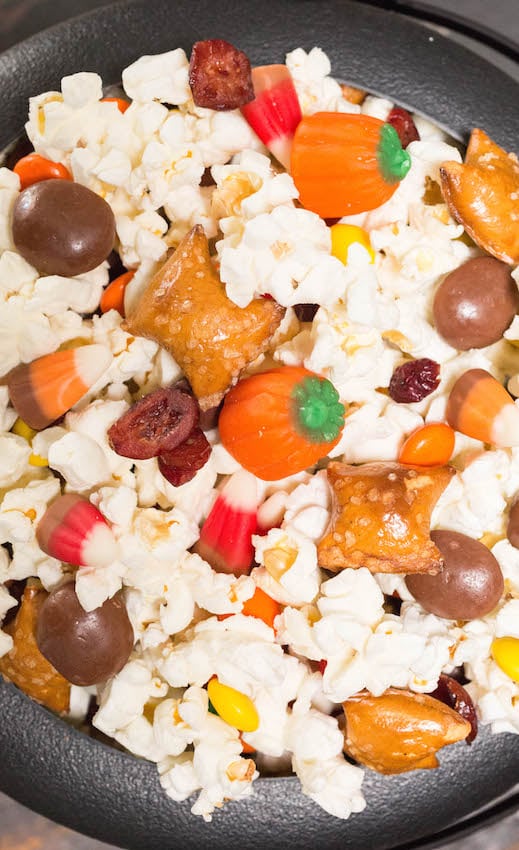 Close up of Halloween Movie Snack Mix filled with popcorn, candy pumpkins, candy corn, peanut butter filled pretzels, and milk duds.