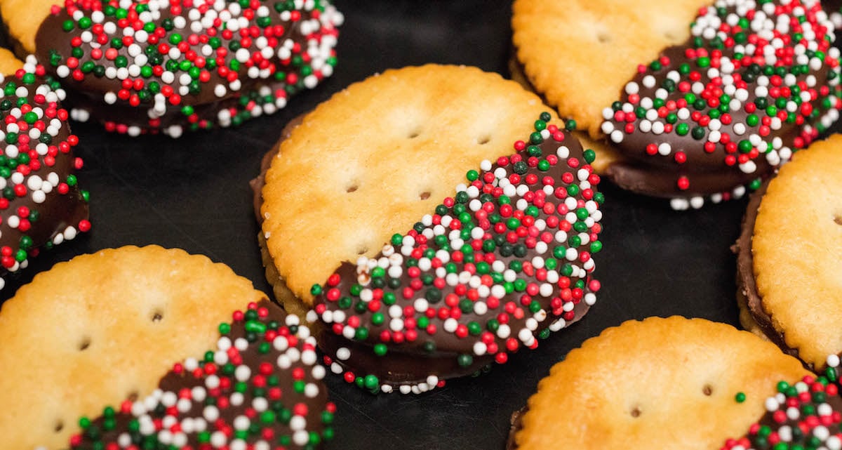 Chocolate dipped Rolo stuffed Christmas Ritz Crackers on a black background.