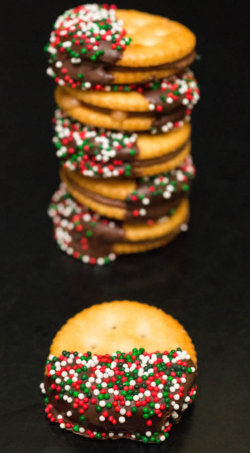 A Chocolate Dipped Rolo Ritz Christmas Cracker in front of a stack of more of them.