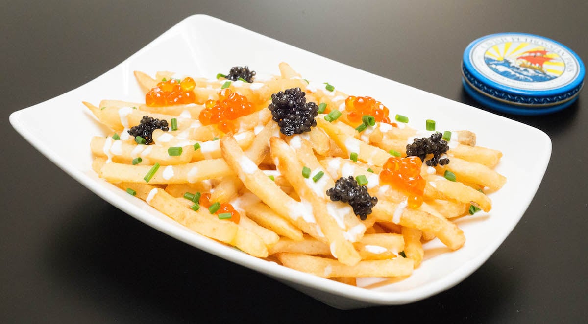 A white serving dish with Caviar French Fries in front of a tin of caviar.
