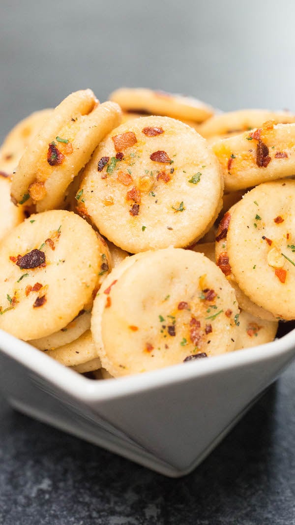 Close up of a Ritz Bits cheese cracker sandwich that's covered in red pepper flakes and ranch seasoning. 