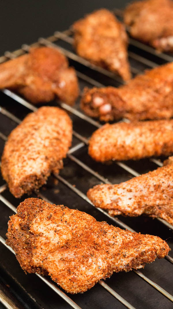 Raw seasoned chicken wings on a baking rack before going in the smoker.