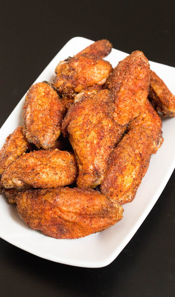 A plate of smoked chicken wings on a black background.