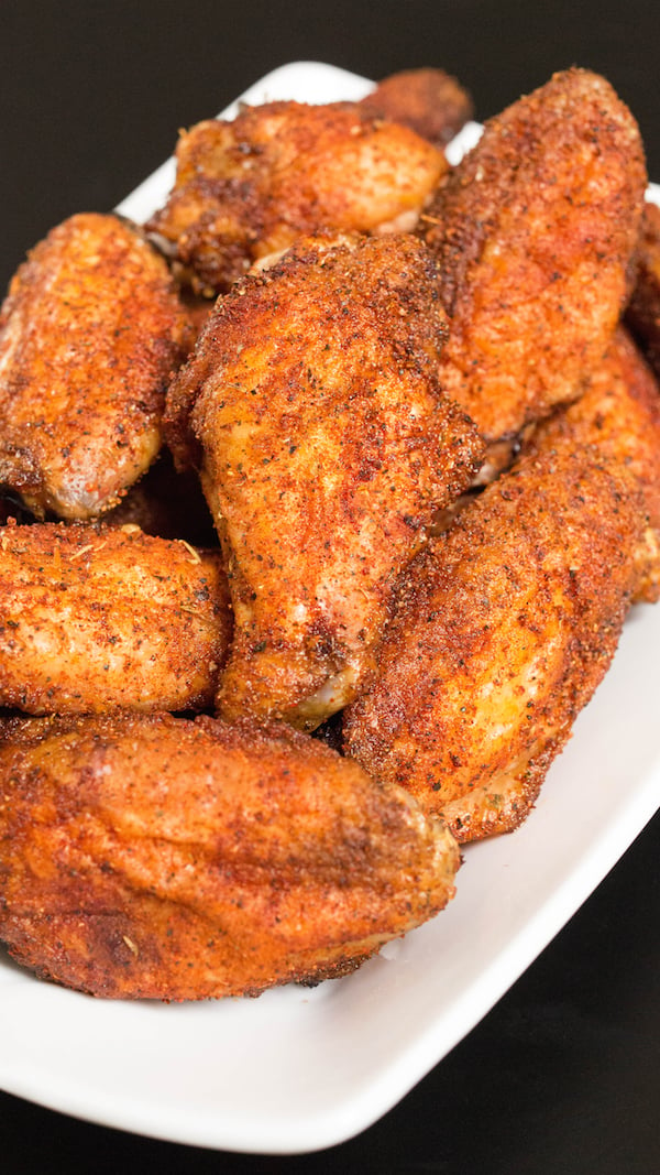 Close up of Smoked Chicken Wings on a white serving plate on a black background.