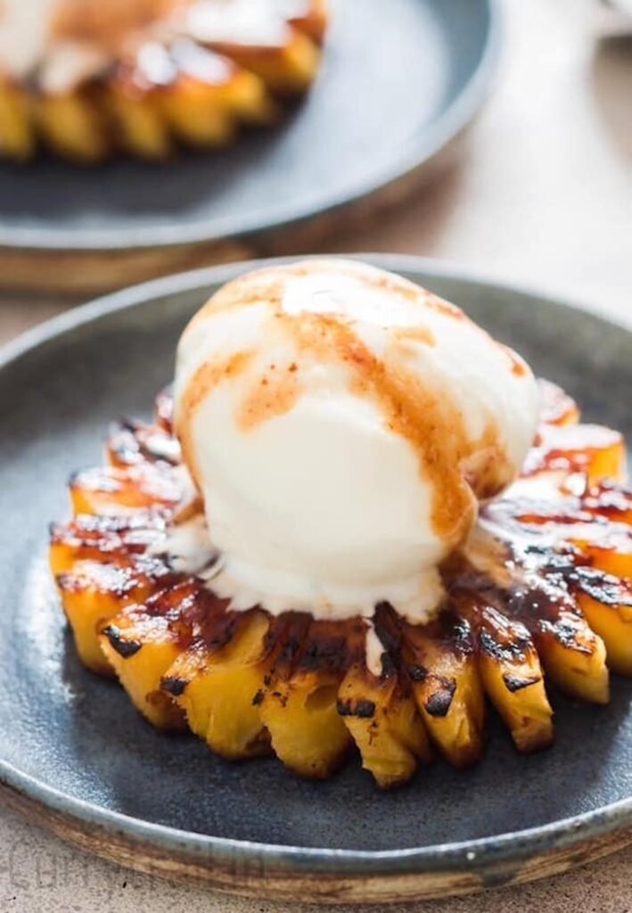 A thick slice of grilled pineapple that's generously topped with a scoop of vanilla ice cream and drizzled with a brown sugar rum glaze.