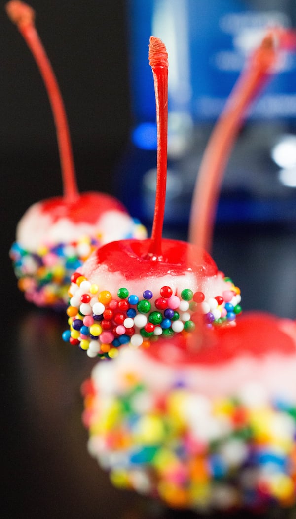 Three Birthday Cake Vodka Cherries on a black background.