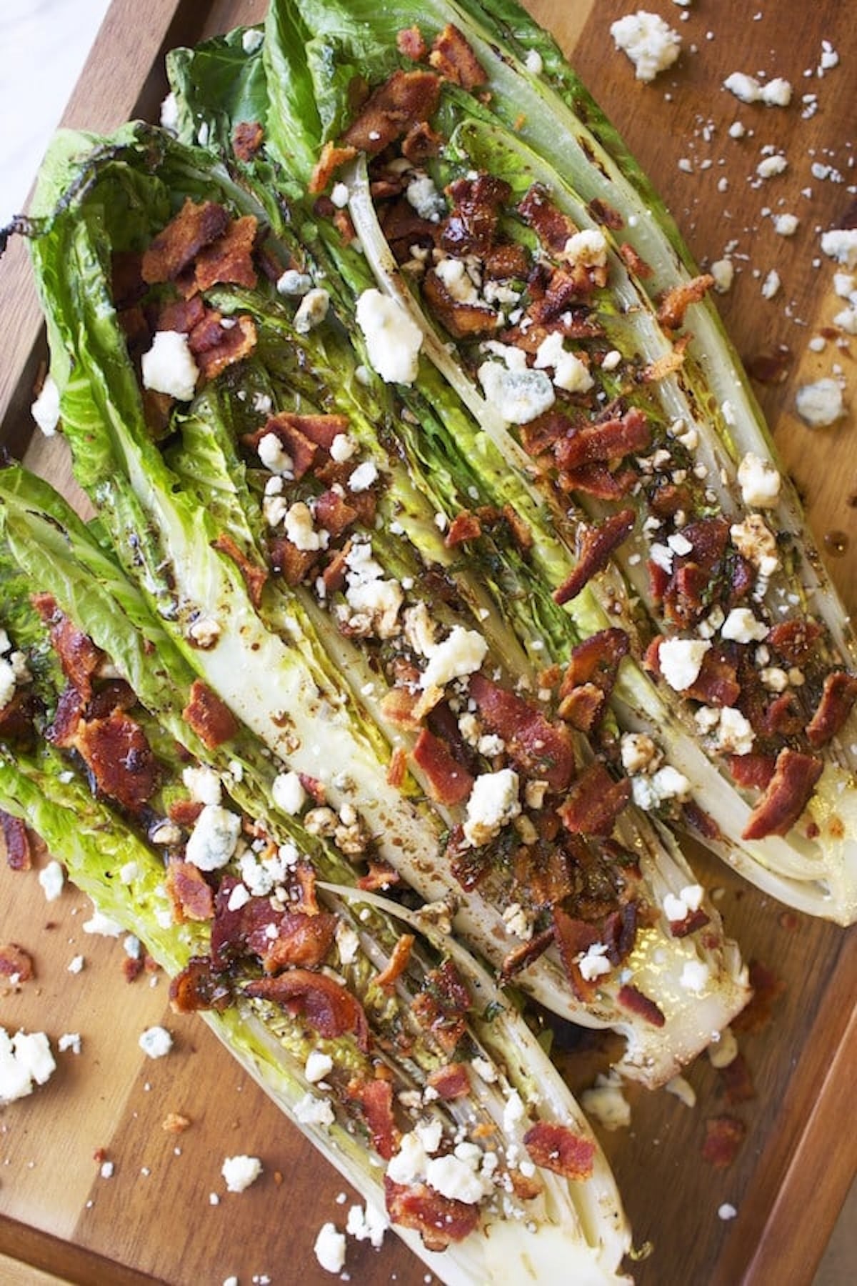 Hearts of grill romaine stuffed with chopped bacon and bleu cheese on a wooden board.
