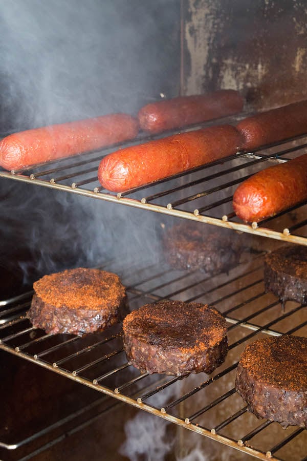 Smoked hamburgers and hot dogs on racks in an electric smoker.