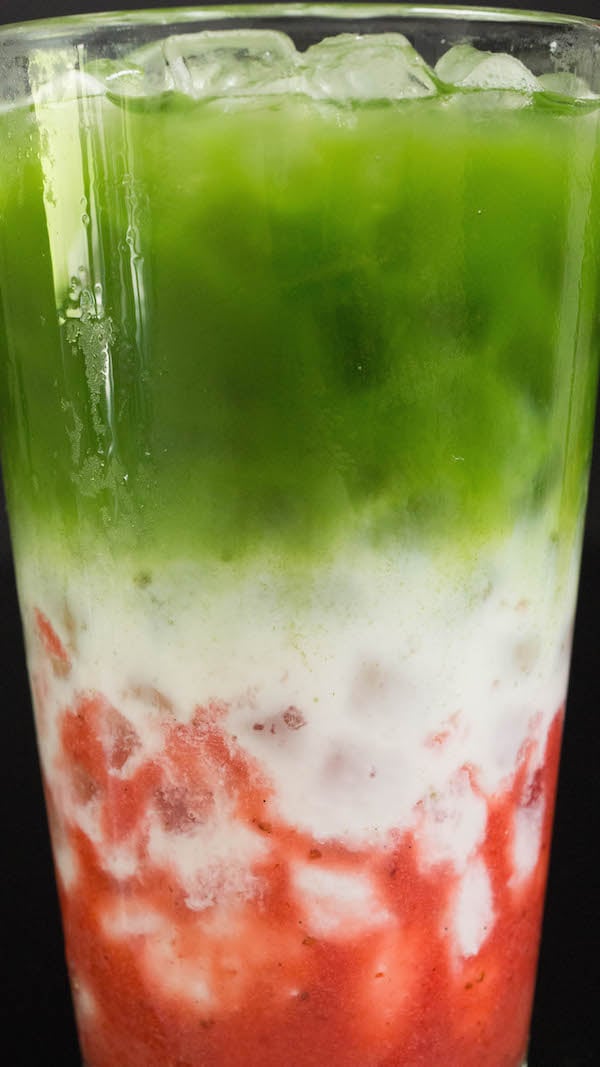 Close up of the three layers of strawberry matcha latte - strawberry syrup, milk, and matcha.