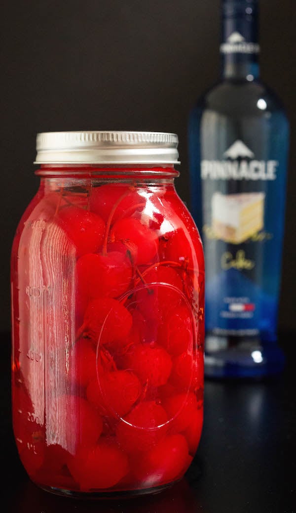 A mason jar of maraschino cherries stacking in cake vodka.