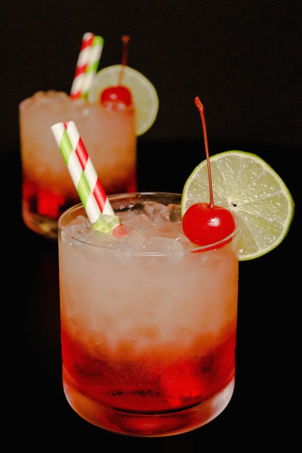 Two layered Cherry Limeade Vodka Drinks on a black background.