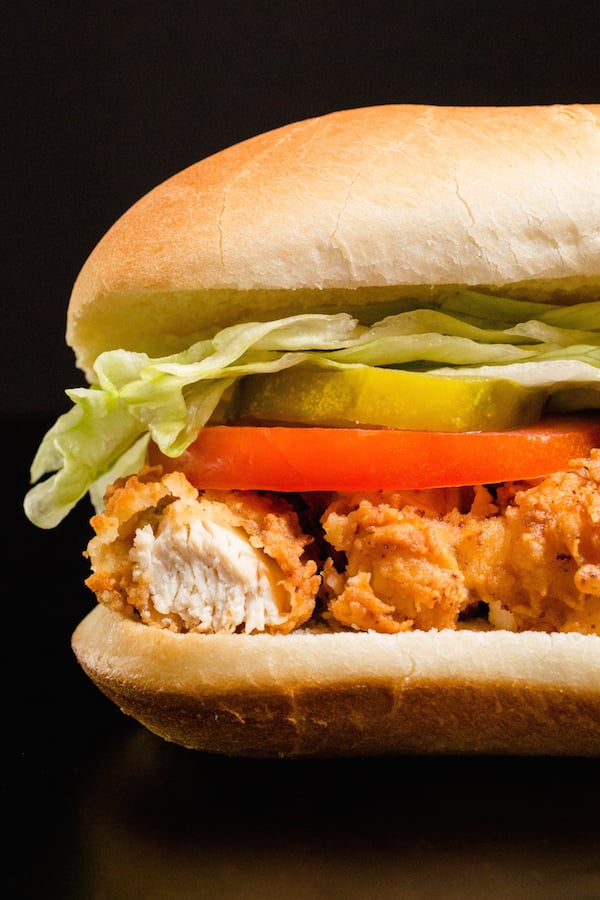 Homemade Chicken Tender Sub Sandwich on a black background.