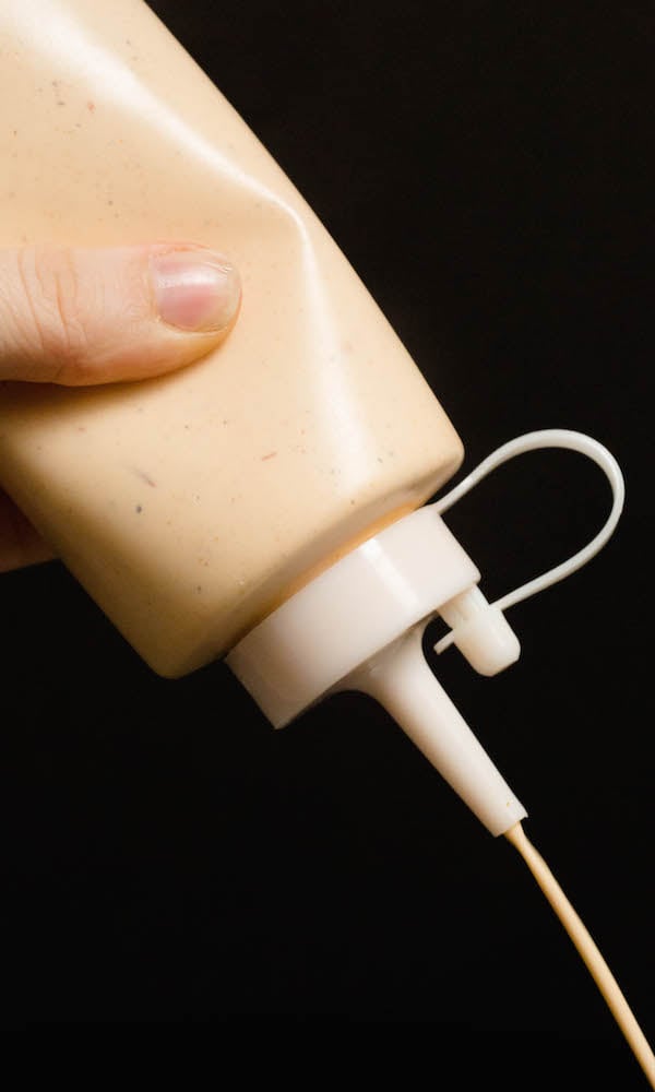 Homemade Alabama White Sauce being squeezed out of the bottle.