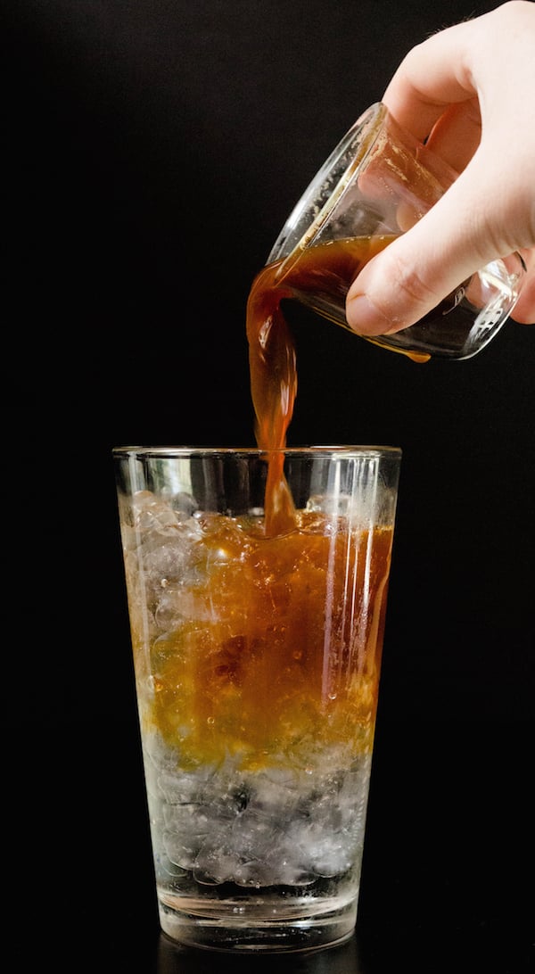 An espresso shot being poured in to a Sparkling Iced Coffee on a black background.
