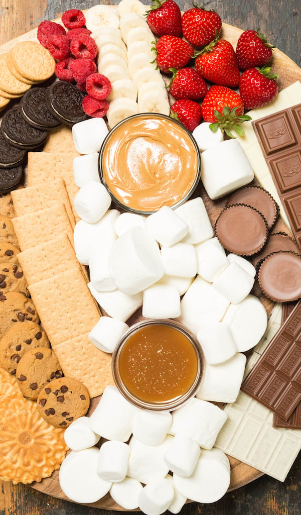 S'mores board marshmallows and toppings like fresh fruit, caramel, and peanut butter.