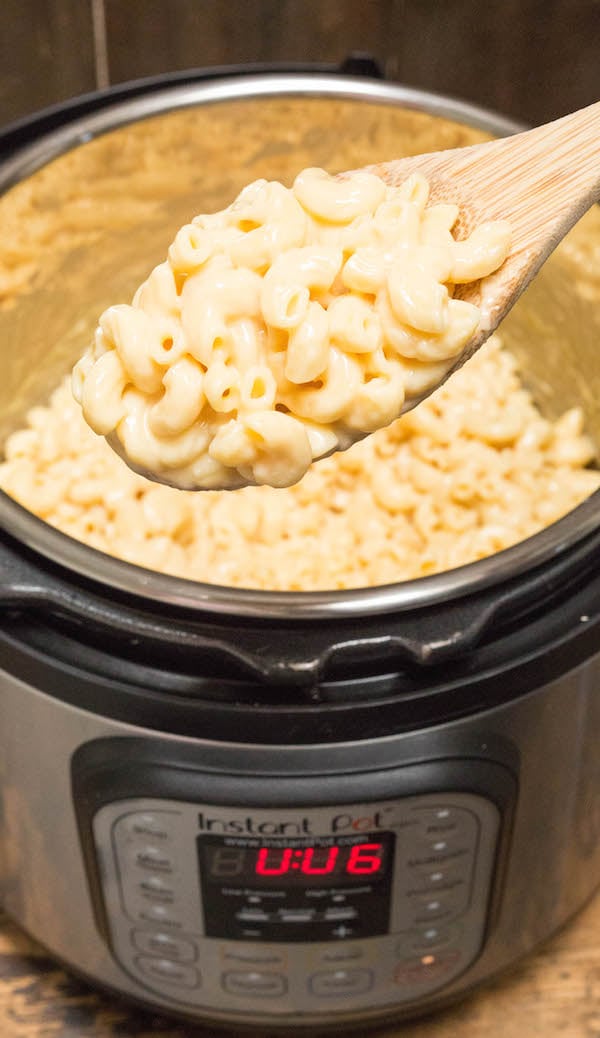 A spoon holding Instant Pot Mac & Cheese over the appliance.