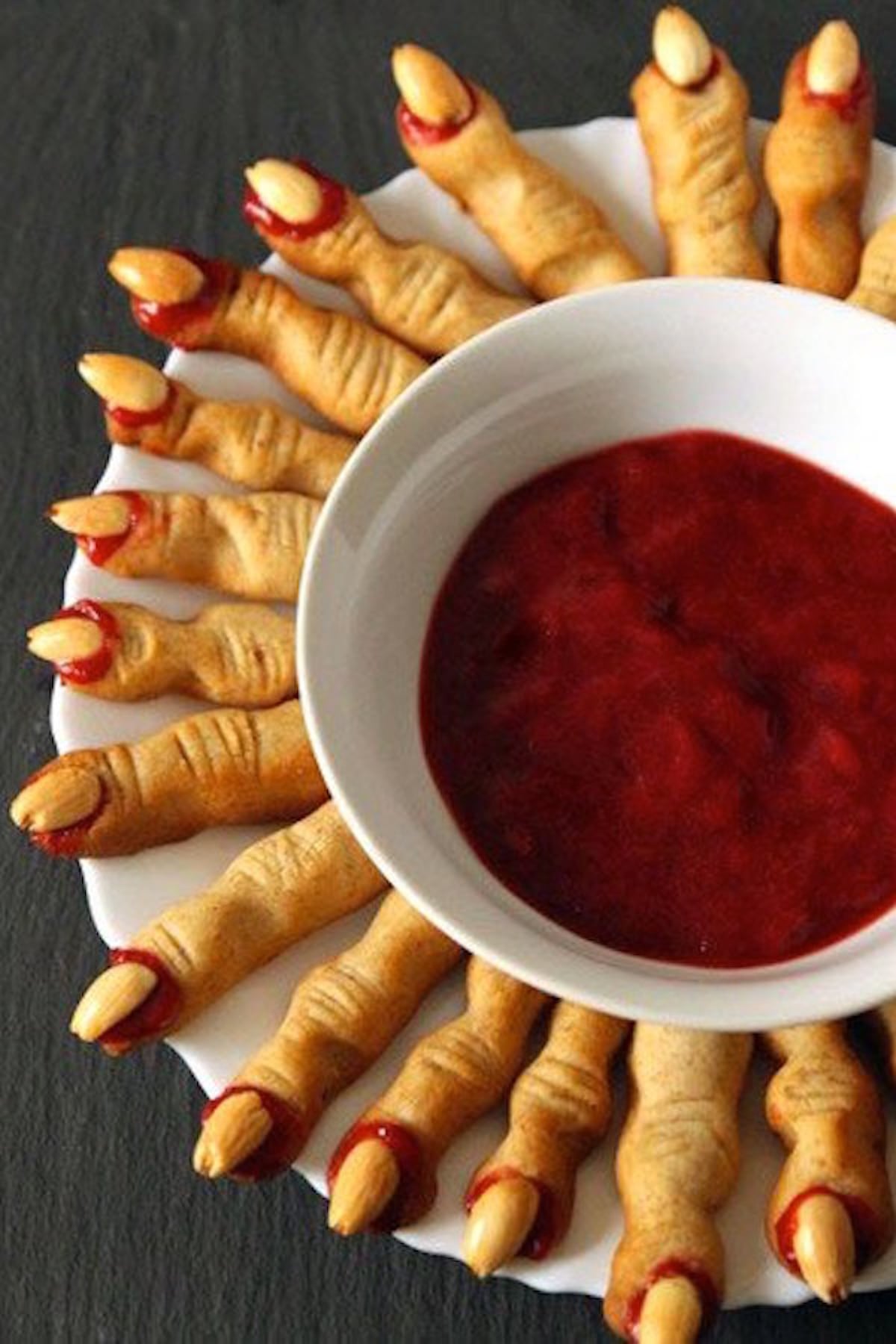 Crackers are cooked in the shape of crooked witch fingers and nuts are attached with a red sauce to look like fingernails.