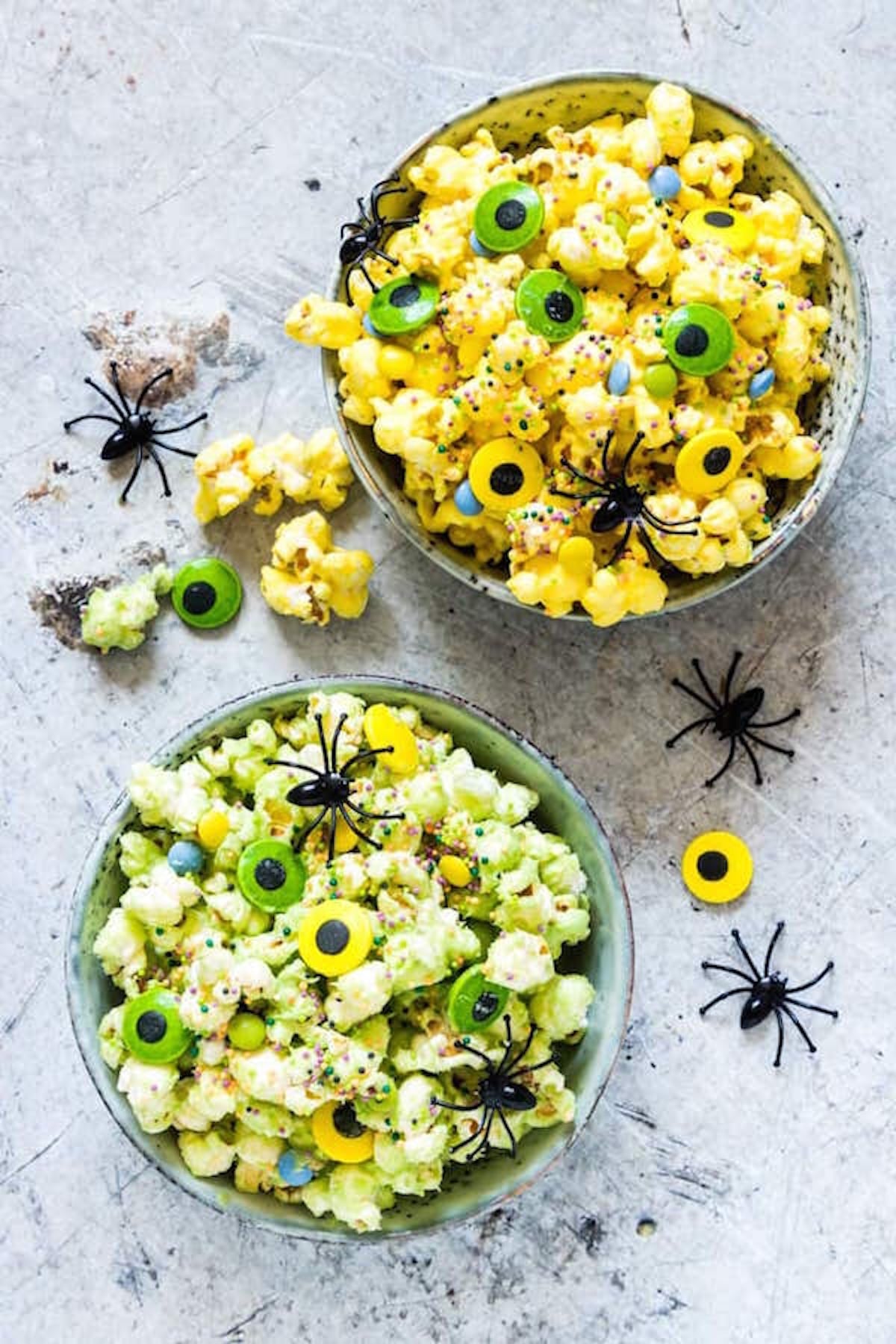 Green colored popcorn coated with halloween sprinkles and garnished with green and yellow candied eyes.