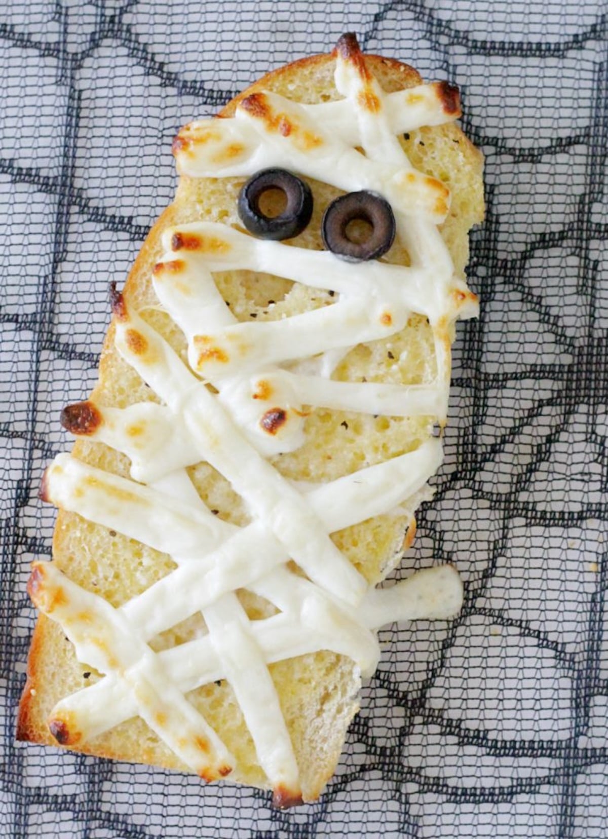 A piece of garlic bread that has strips of white cheese melted to make it look like a money. Black olives are used for eyes.