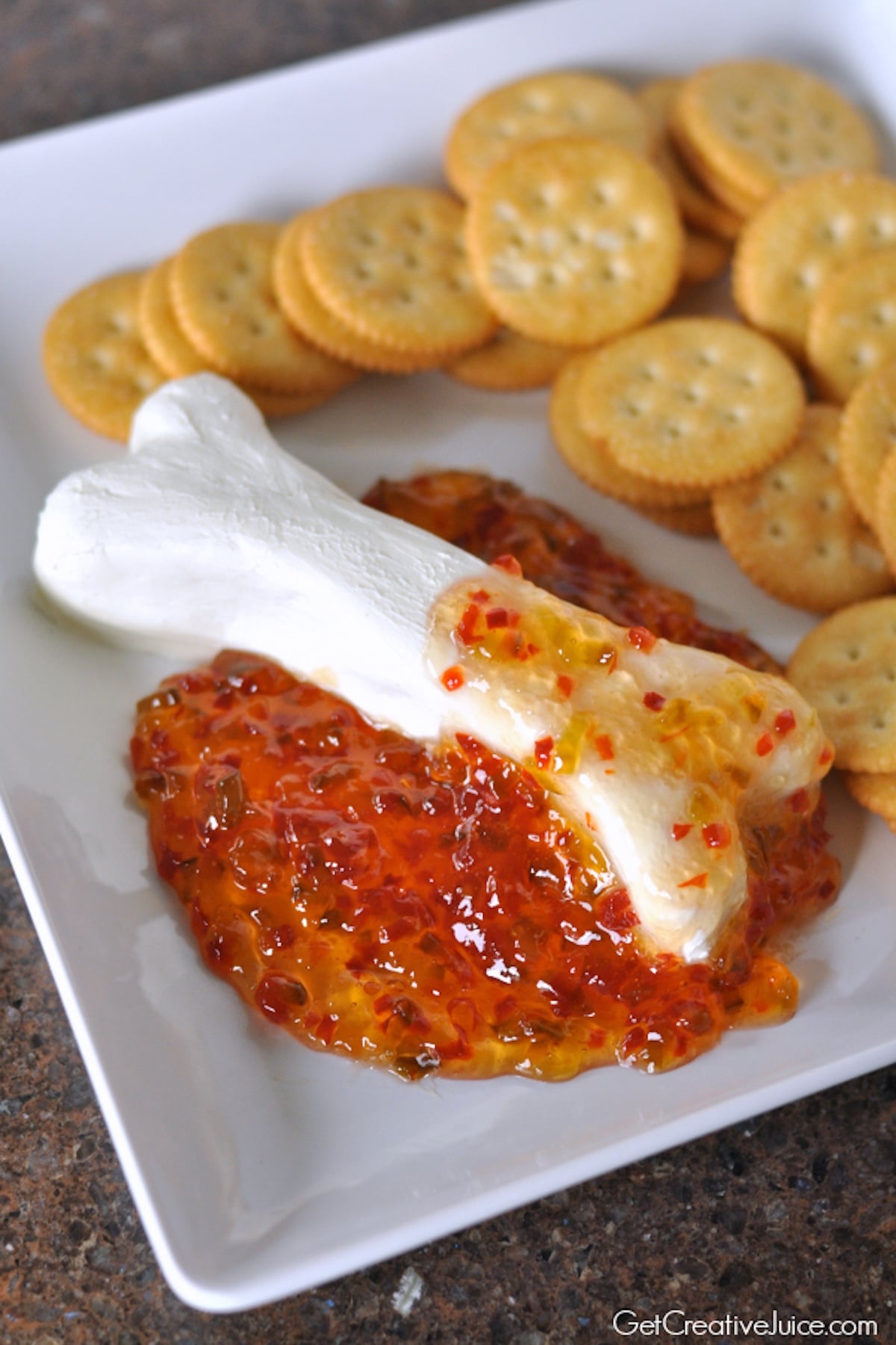 A block of cream cheese has been cut into a bone shape and covered in red pepper jelly.