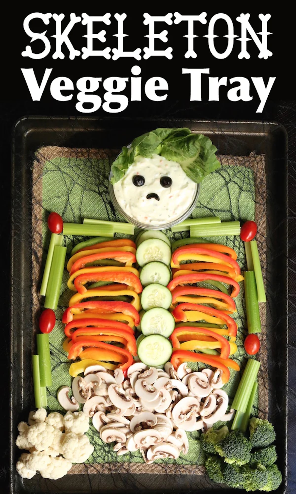 A skeleton made of veggies using celery for the arms, bell pepper slices for the ribs, mushrooms for the guts, and broccoli and cauliflower as hands. Is face is made of a small bowl of ranch with olives for eyes.