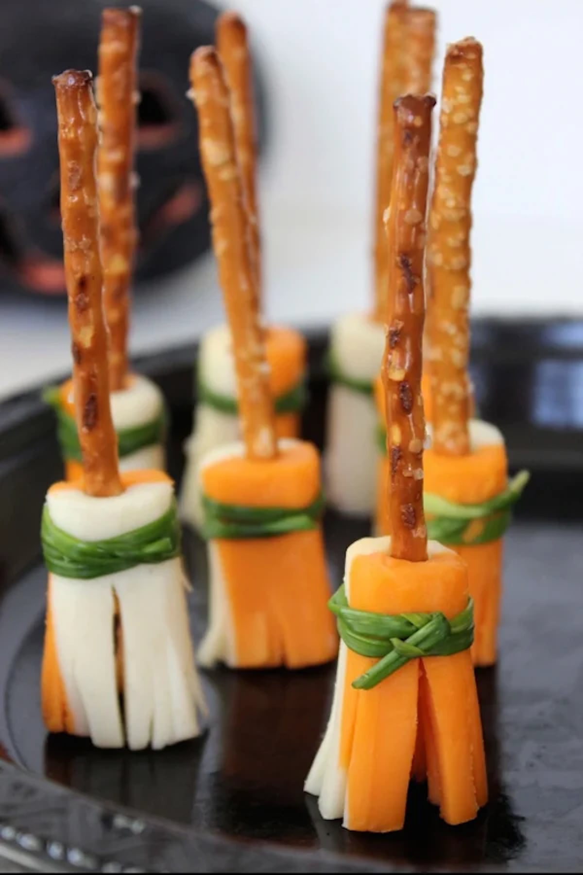 Cheese sticks have been cut and frayed to look like broomsticks. Pretzel sticks are used as handles.