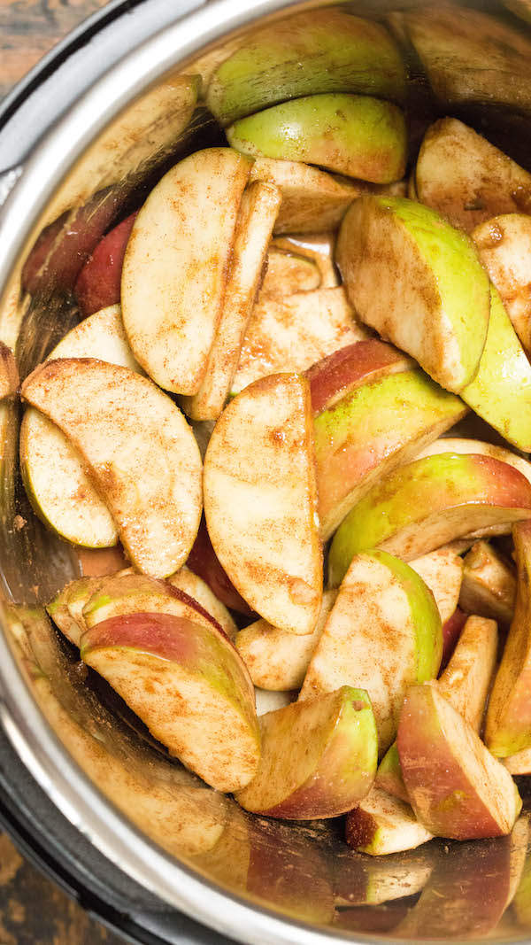 Apple cider being poured over sliced apples and brown sugar in the Instant Pot to make apple butter.