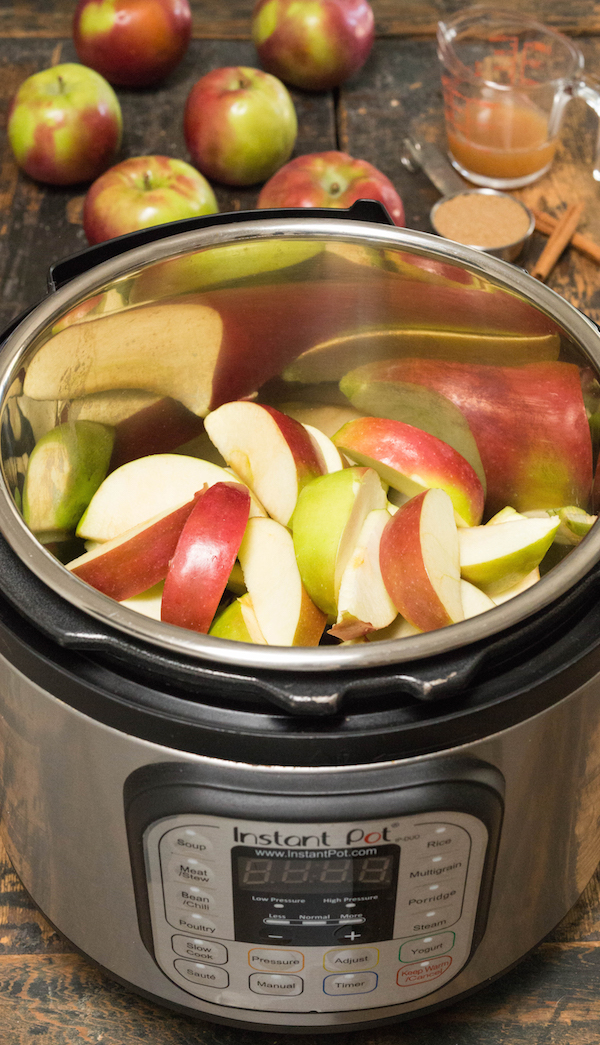 An Instant Pot filled with sliced apples and other apple butter ingredients.