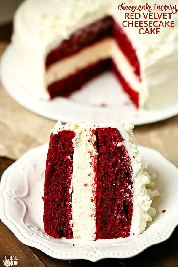 A slice of Layered Red Velvet Cheesecake Cake on a white plate with the rest of the cake in the background