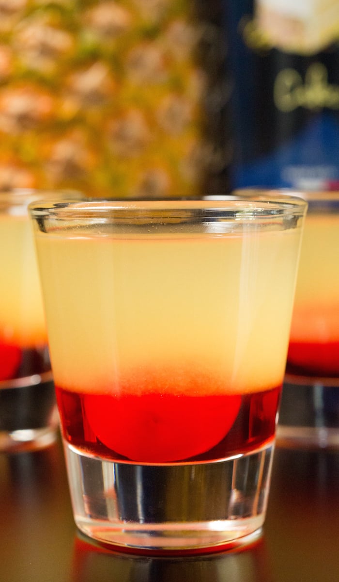 Close up of a layered pineapple upside-down cake shot with a blurred out black background.