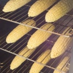 Three racks of corn inside a smoker