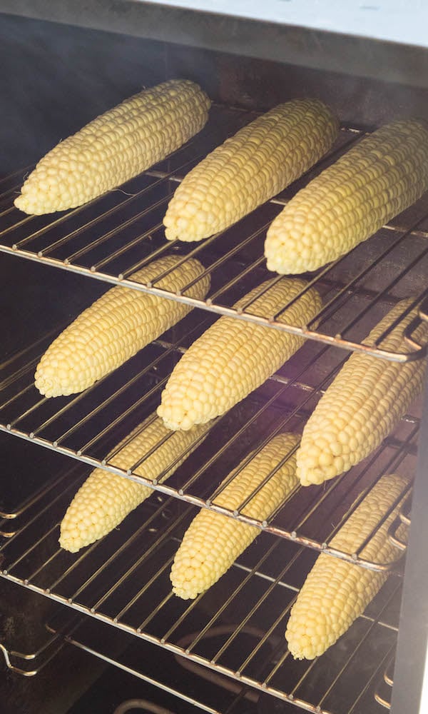Three racks of corn inside a smoker