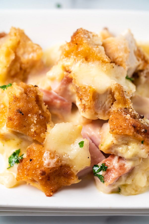 Close up of a piece of Chicken Cordon Bleu Casserole on a white dish