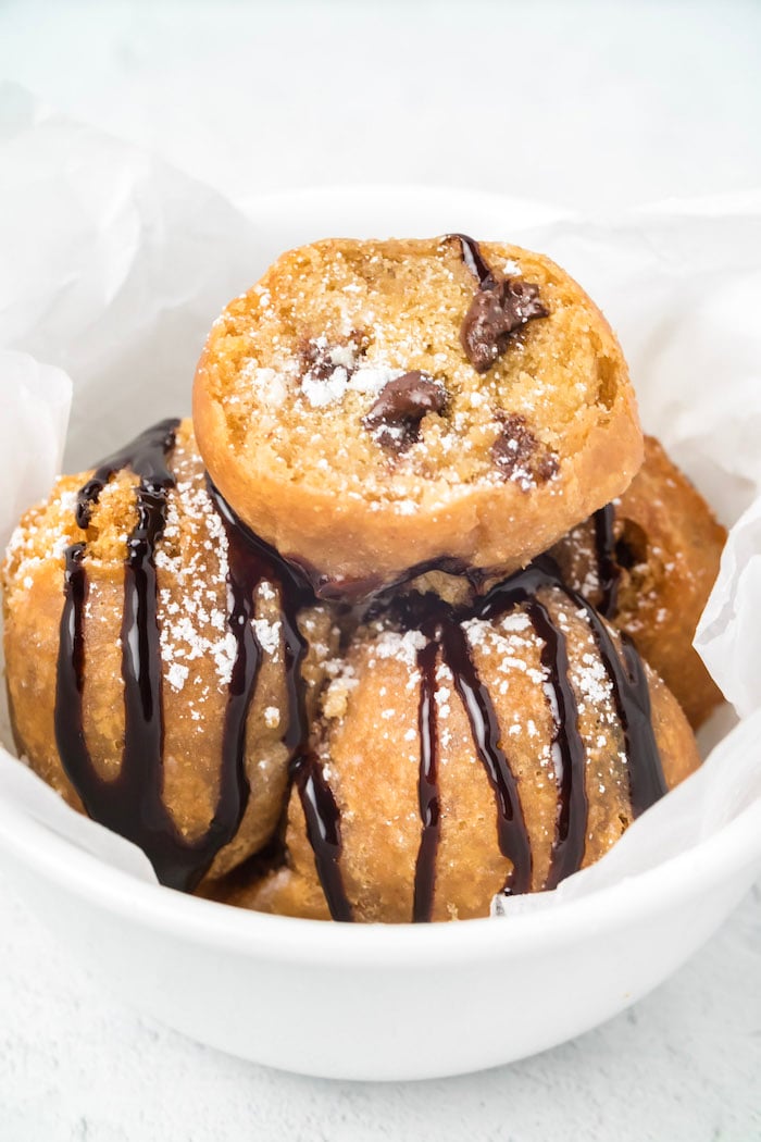 A bowl of fried cookie dough balls covered in chocolate syrup