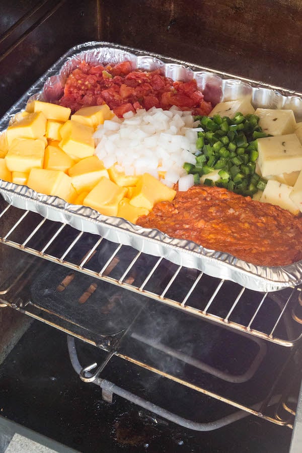 A pan of smoked queso ingredients inside an electric smoker