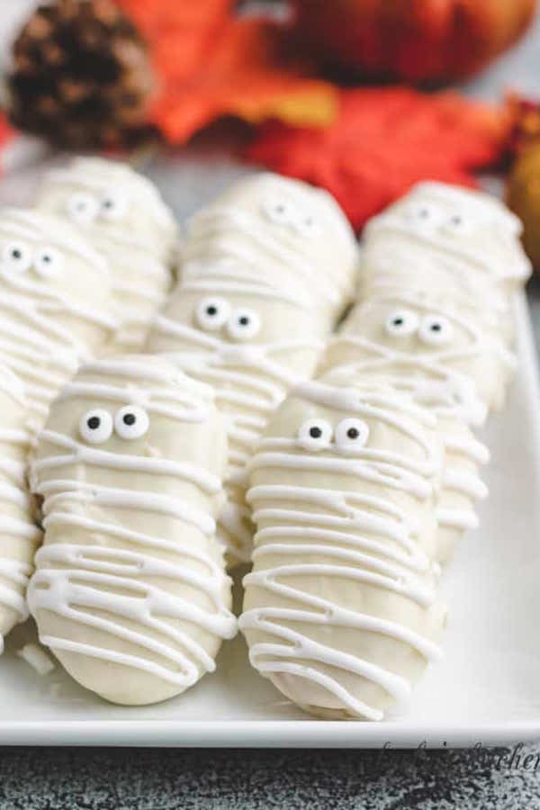 A batch of nutter butter cookies glazed with white chocolate to look like mummies for Halloween
