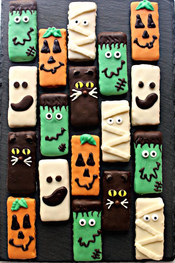 Graham crackers covered in chocolate then decorated with icing and candy eyes to look like jack-o-lanterns, ghosts, black cats, frankensteins, and mummies