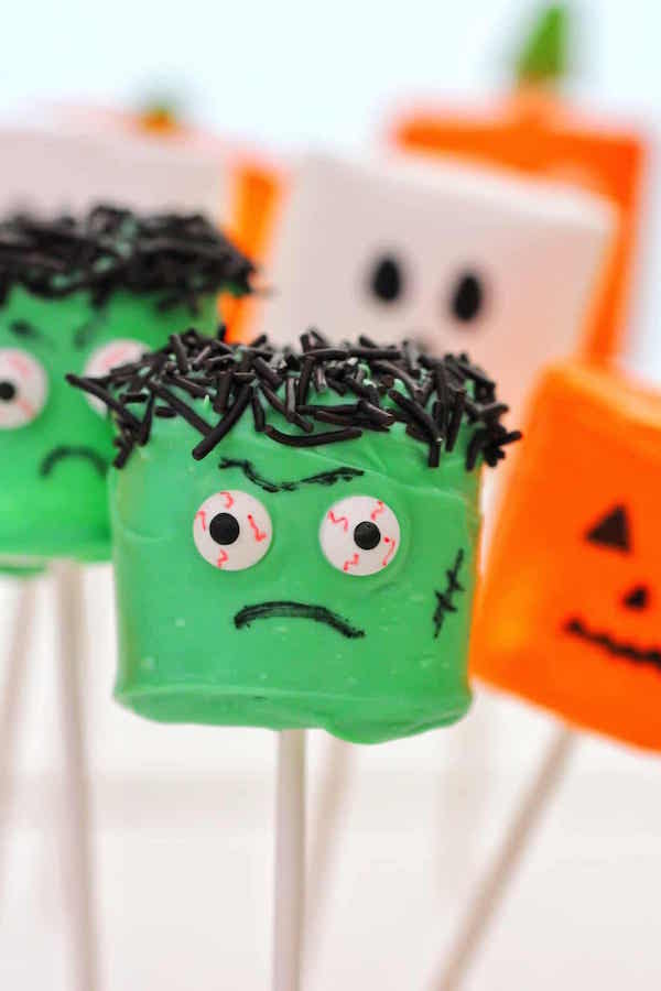 Marshmallows on sticks decorated to look like Frankenstein, Jack-o-lanterns, and ghosts for Halloween.