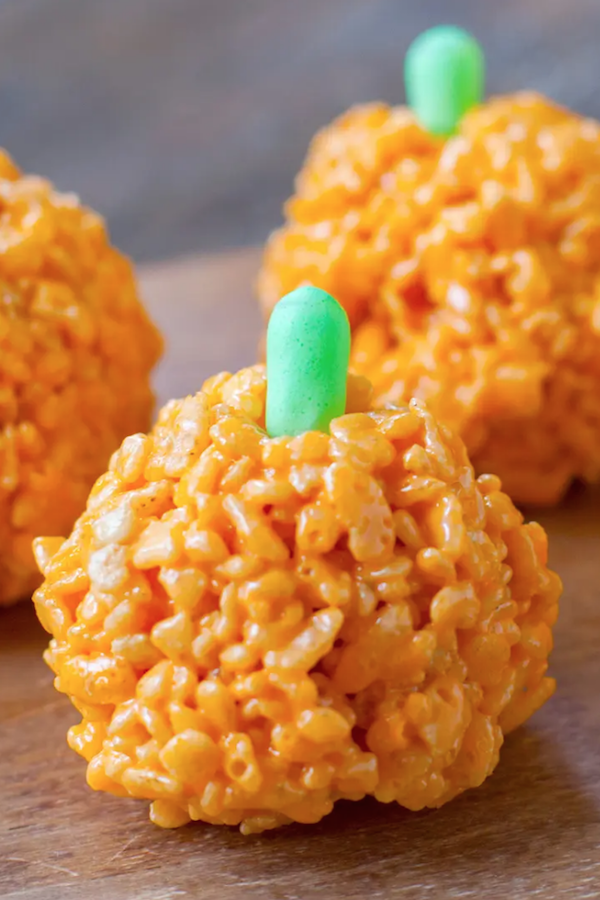 An orange Rice Krispie treat in the shape of a pumpkin with a green candy on top for the stem.