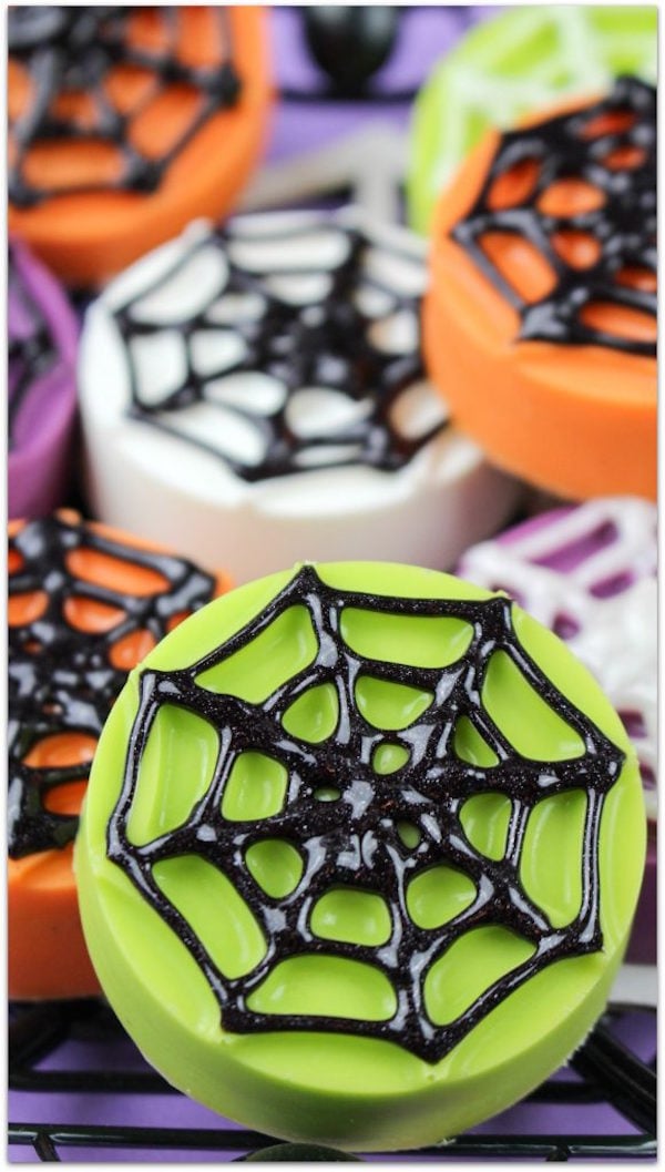 Oreos covered in neon green, white, and orange chocolate then decorated on top with black spider webs