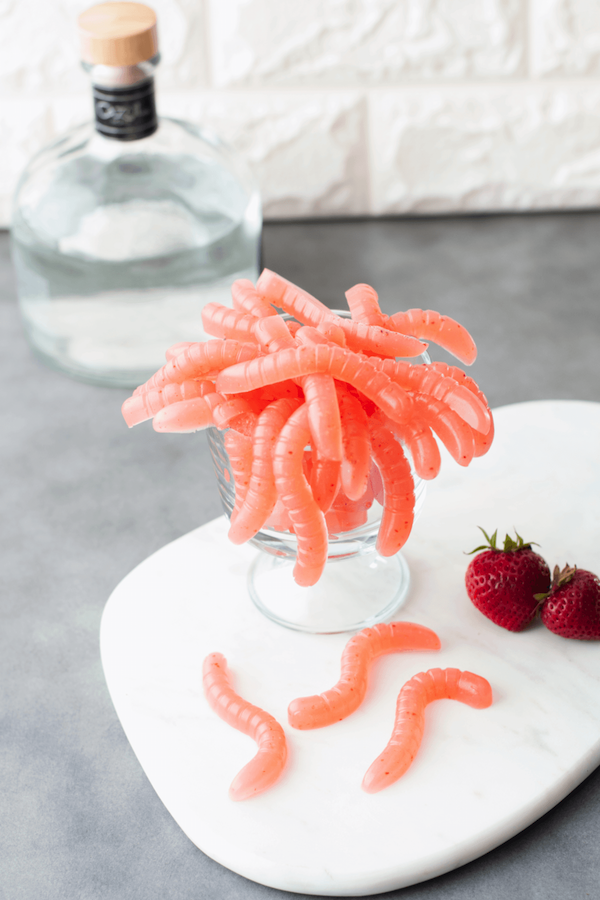 A glass bowl full of bright pink homemade strawberry margarita gummy worms.
