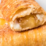 Close up of an apple cheesecake chimichanga that has been cut open on the end to show the cream cheese and apple pie filling